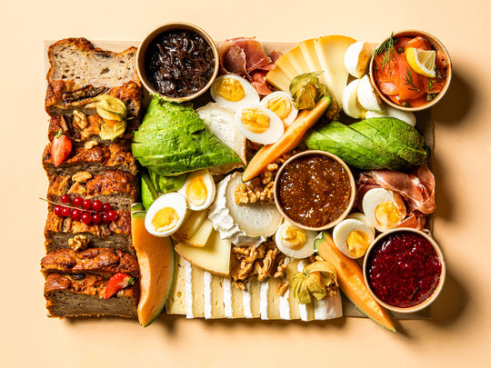Brunch Platte von Feasts of Eden mit Banana Bread, Avocado, Eiern, Obst, Käsevariationen, Prosciutto, Marmeladen, Chutney, Lachs und Nüssen