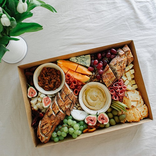 Grazing Box mit Wurst, Käse, Chutney, Humus, Obst und Baguette